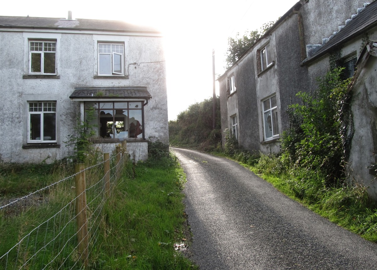Title: Derelict houses on the L7056 at Ballinteskin. Copyright: Eric Jones. License: cc-by-sa/2.0. Source: https://www.geograph.ie/photo/5129670
